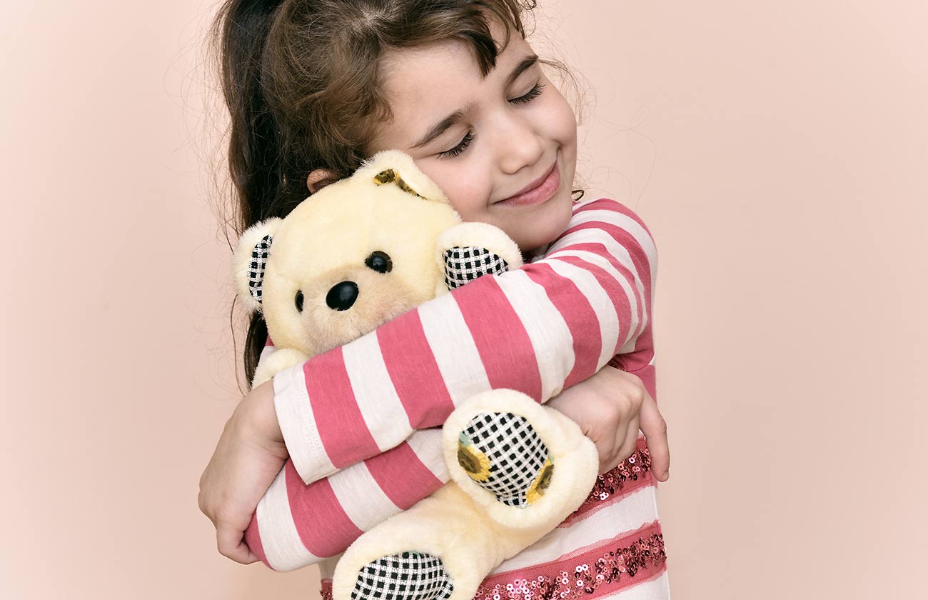 Bambina che abbraccia il suo peluche del cuore